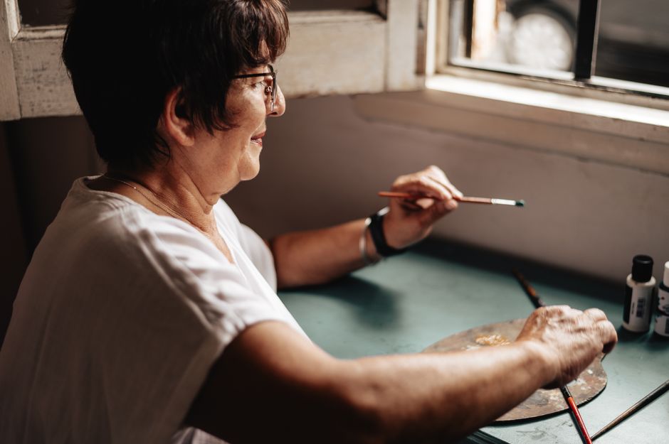 A senior woman enjoying a painting session, illustrating art therapy.