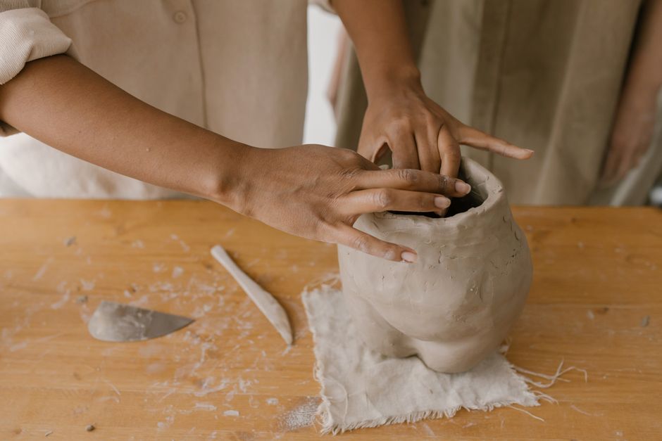 Hands molding a clay sculpture.